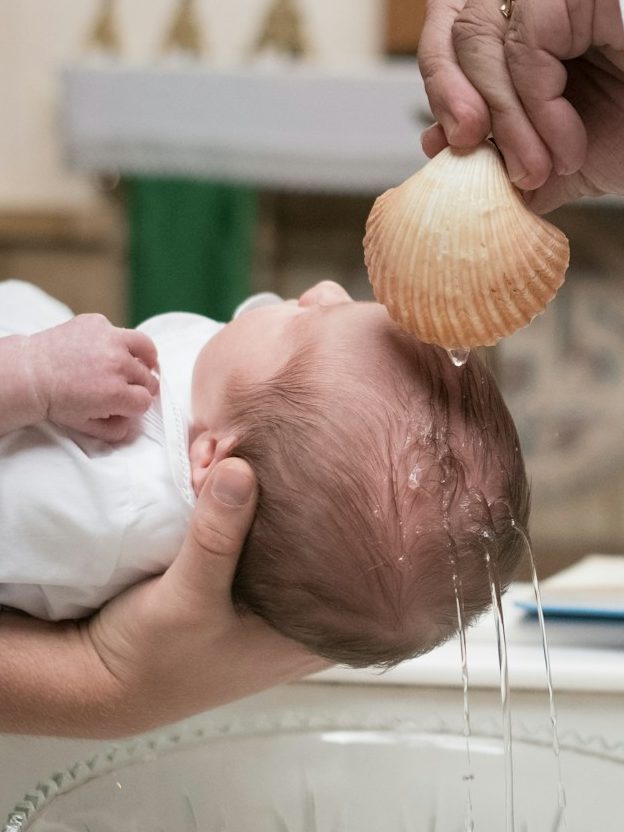 Taufe eines Babys mit Taufwasser