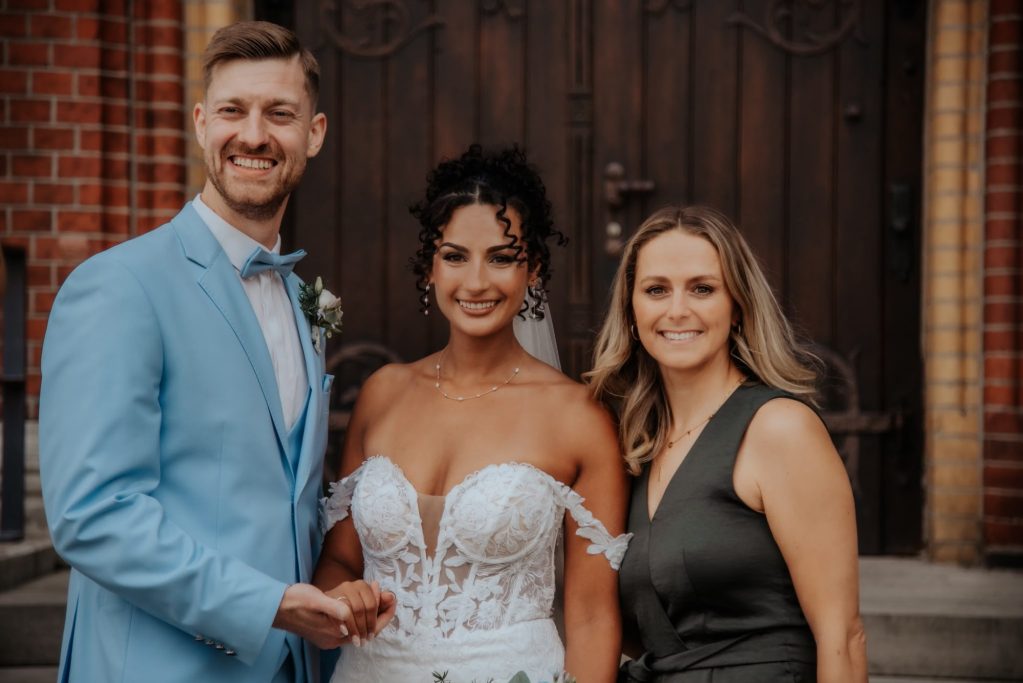 Brautpaar mit Hochzeitssängerin Chantal Will vor der Kirche