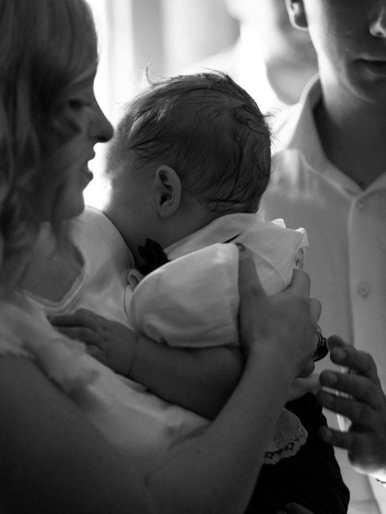 Familie hält ein Baby nach der Taufe im Arm