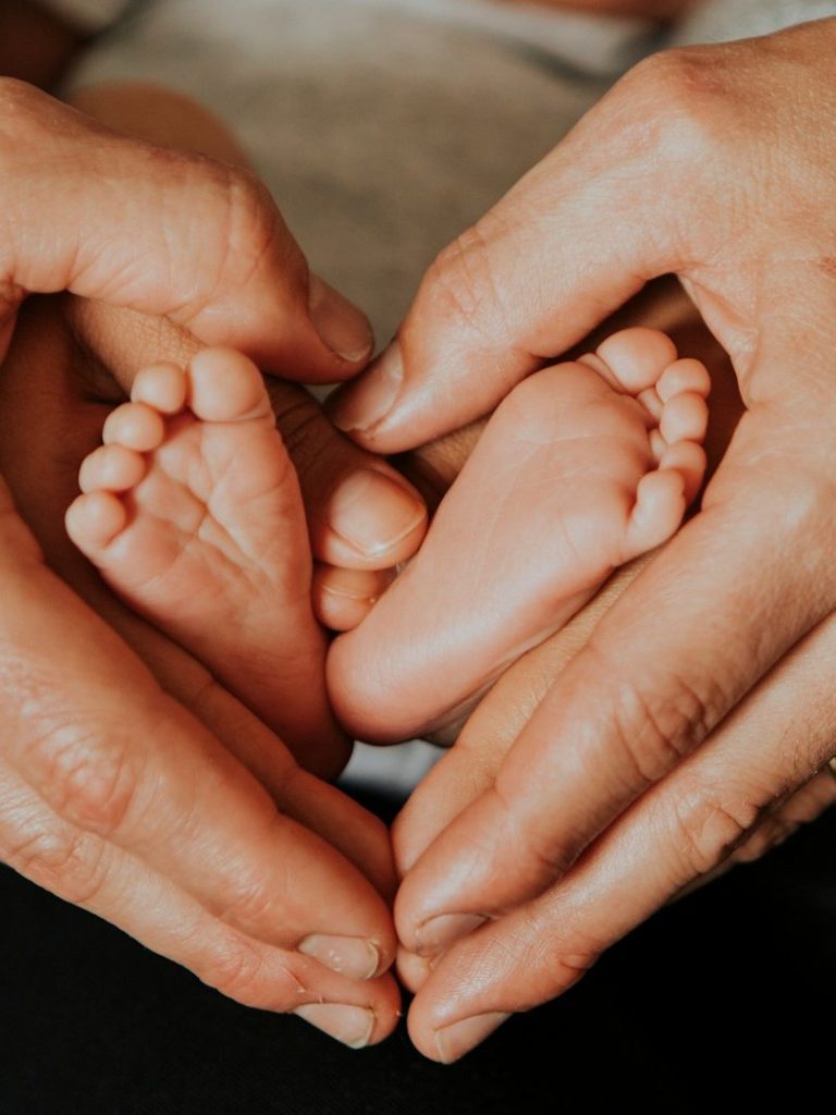 Babyfüße in den schützenden Händen der Eltern