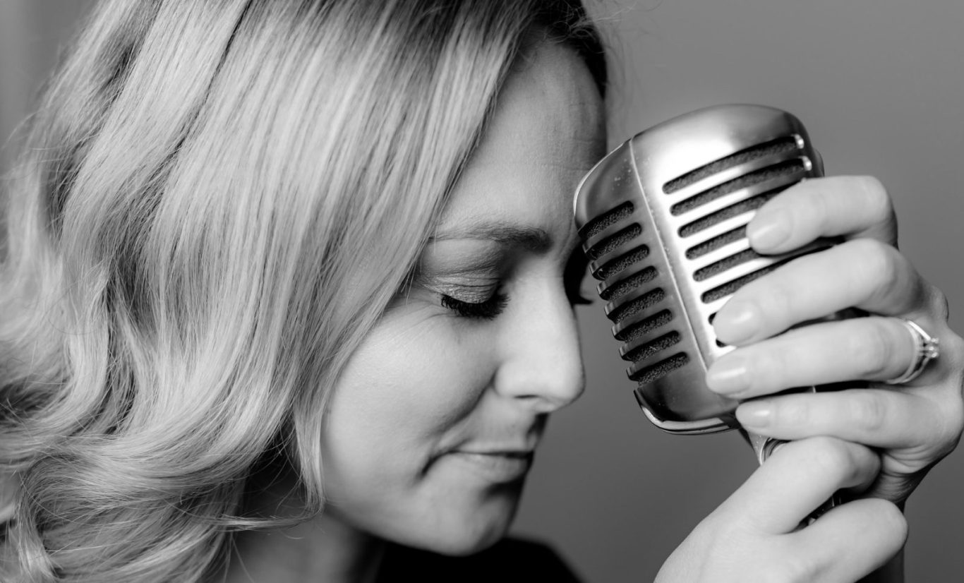 Chantal Will mit einem klassischen Mikrofon in Schwarz-Weiß